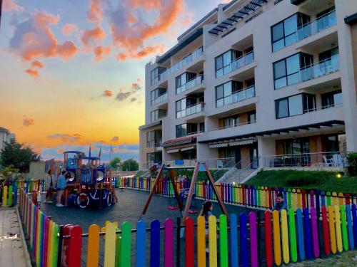 einen bunten Zaun mit einem Spielplatz vor einem Gebäude in der Unterkunft Obzor Beach Resort in Obsor