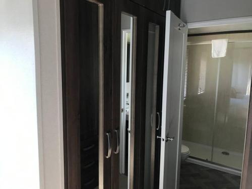 a bathroom with a toilet and a glass door at Bramble Lodge with Hot Tub in York