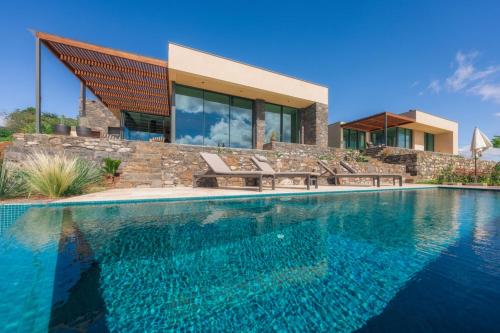 a house with a swimming pool in front of a house at The Rock Villas in Estreito da Calheta