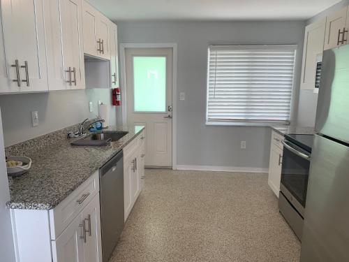 a kitchen with white cabinets and a sink and a window at Ocean Eleven Suites in New Smyrna Beach