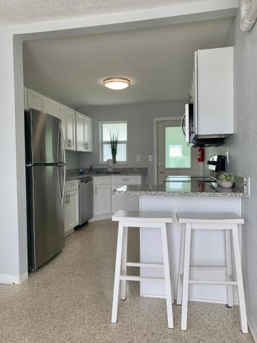 a kitchen with a stainless steel refrigerator and white cabinets at Ocean Eleven Suites in New Smyrna Beach