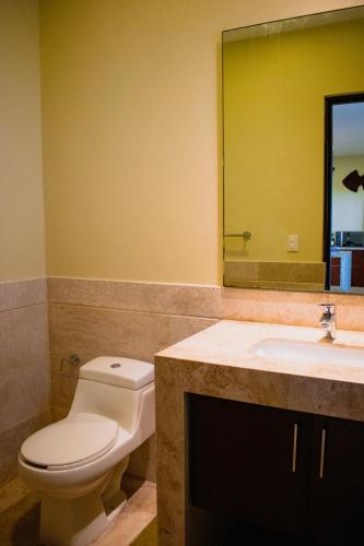 a bathroom with a toilet and a sink and a mirror at Villas Grand Marina Kinuh in Telchac Puerto