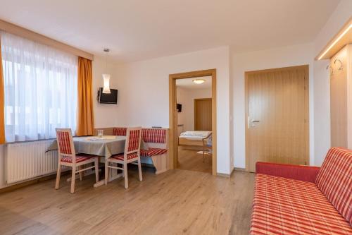 sala de estar con mesa, sillas y sofá en Wiesengrund - Wohnung 1, en Tirolo