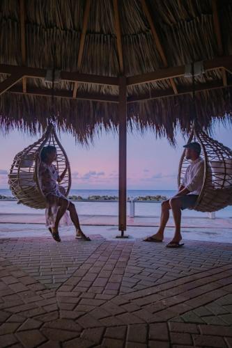 two people sitting in hammocks on a beach at Curacao Avila Beach Hotel in Willemstad
