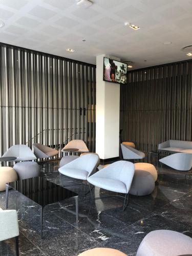a lobby with white chairs and a tv on a wall at Galeria Plaza San Jeronimo in Mexico City