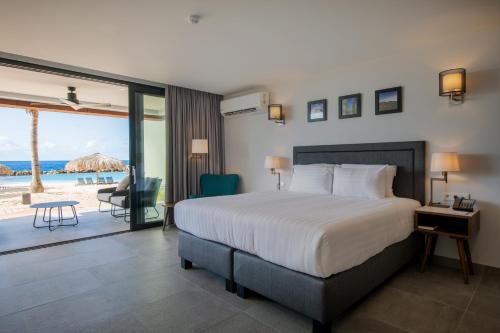 a bedroom with a bed and a view of the beach at Curacao Avila Beach Hotel in Willemstad