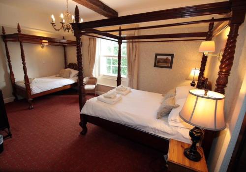 a bedroom with two four poster beds and a lamp at Old Hall Hotel Hope in Hope
