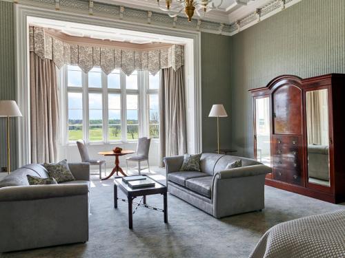 a living room with two couches and a large window at Matfen Hall Hotel, Golf & Spa in Matfen