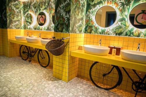 een badkamer met drie wastafels en twee fietsen erin bij The Corner London City in Londen