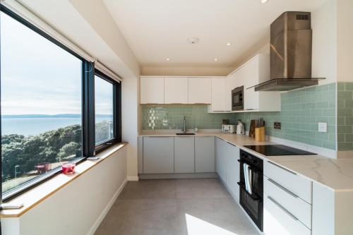 a kitchen with white cabinets and a large window at Westcliff Penthouse in Bournemouth
