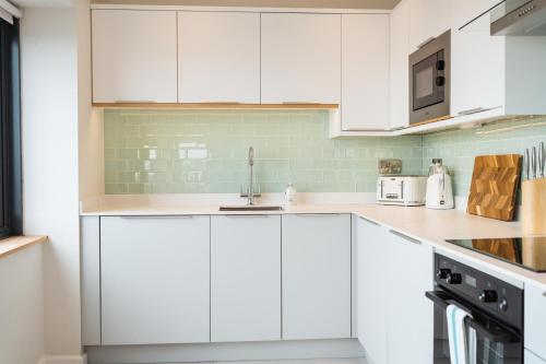 a white kitchen with white cabinets and a sink at Westcliff Penthouse in Bournemouth