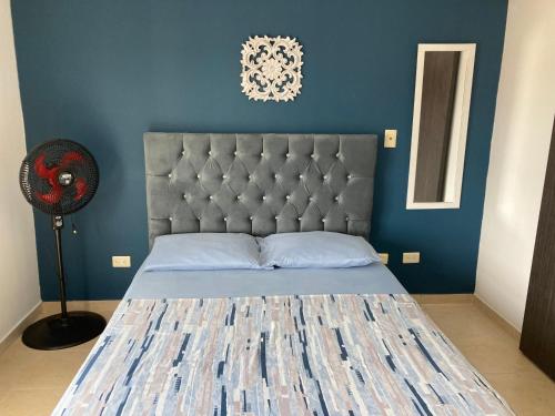 a bedroom with a bed with a blue wall at Aparta- Estudio Amoblado in Ibagué
