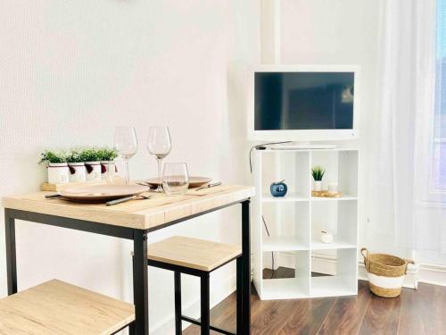 einen Tisch mit Weingläsern und einen TV in einem Zimmer in der Unterkunft STUDIO LUMINEUX - CENTRE VILLE - WIFI in Le Mans