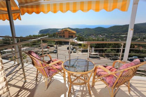a glass table and chairs on a balcony with a view at Eleni Studios Parga in Parga