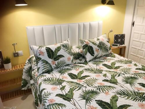 1 dormitorio con cama con colcha y almohadas de flores en El Nido, en Torre del Mar