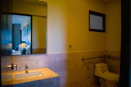 a bathroom with a sink and a toilet and a mirror at Villas Grand Marina Kinuh in Telchac Puerto