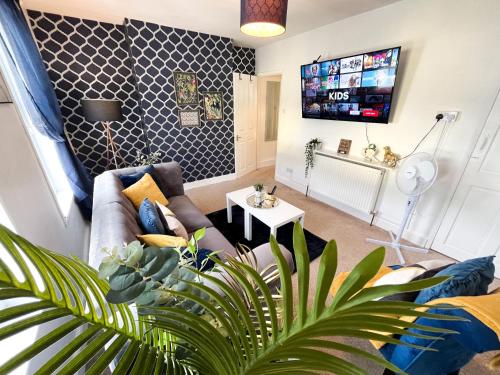 a living room with a couch and a tv at Gillingham Centre Modern Apartment in Gillingham