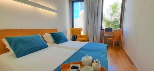 1 dormitorio con cama con almohadas azules y escritorio en Boavista Class Inn, en Oporto