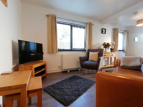 a living room with a flat screen tv and a couch at Cottage by the river in Cenarth with seasonal fishing and Wifi in Cenarth