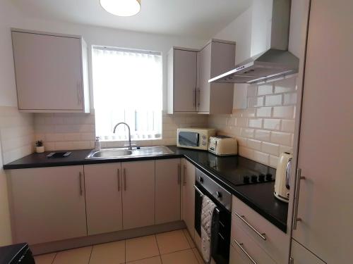 a kitchen with white cabinets and a sink and a window at Cottage by the river in Cenarth with fishing and Wifi in Cenarth