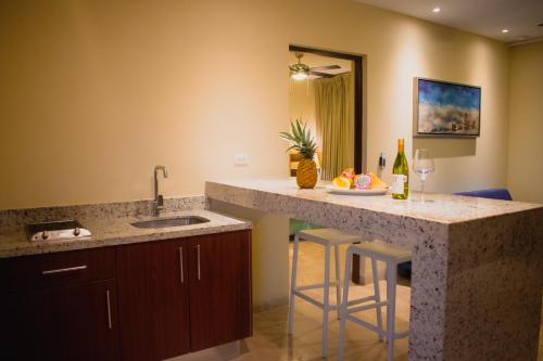 a kitchen with a counter with a sink and bar stools at Villas Grand Marina Kinuh in Telchac Puerto