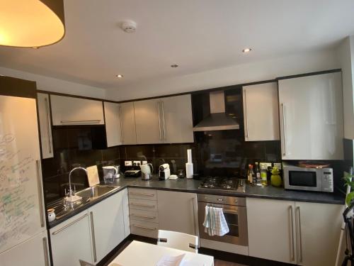 eine Küche mit weißen Schränken und Küchengeräten aus Edelstahl in der Unterkunft Notting Hill Next Door Bedroom in the share flat in London