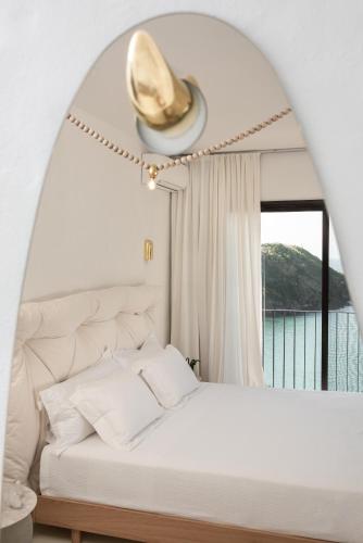 a bedroom with a white bed with a large window at Miradouro de São Sebastião in São Sebastião
