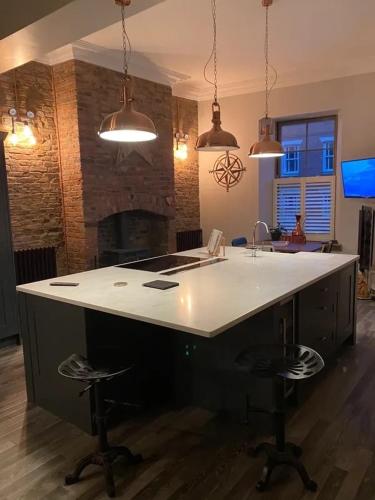 a kitchen with a counter with stools and a fireplace at Newgate House in Morpeth
