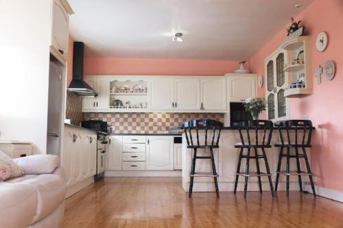 uma cozinha com armários brancos e uma parede rosa em The Village Inn em Mayo