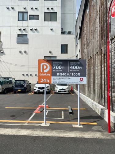 un estacionamiento con una señal de estacionamiento frente a un edificio en 瓦町駅•home 101, en Takamatsu