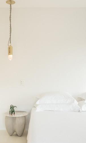 a white bedroom with a bed and a table at Miradouro de São Sebastião in São Sebastião