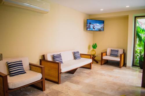 a living room with two chairs and a tv at Villas Grand Marina Kinuh in Telchac Puerto