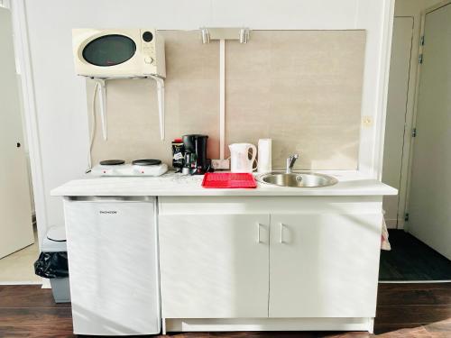 eine kleine weiße Küche mit einer Spüle und einer Mikrowelle in der Unterkunft STUDIO LUMINEUX - CENTRE VILLE - WIFI in Le Mans