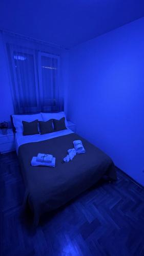 a blue room with a bed with towels on it at Paunov Breg in Jajinci
