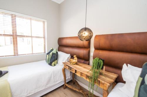 a room with a bed and a table with a bench at Plettenberg Bay Unit 10 Whale Rock Gardens Apartment in Plettenberg Bay
