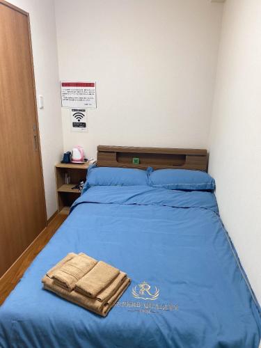 a bed with blue sheets and two towels on it at 瓦町駅•home 101 in Takamatsu