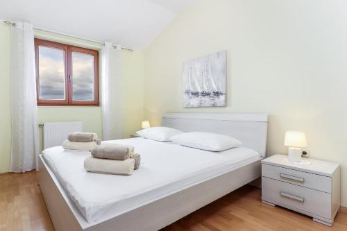 a white bedroom with a white bed and a window at Maris in Rab