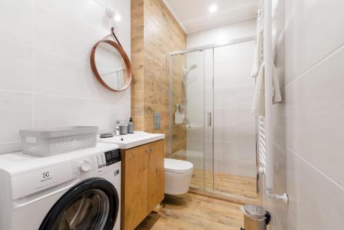 a washing machine in a bathroom with a shower at Apartamenty przy Ścieżce Kościelnej in Elblag