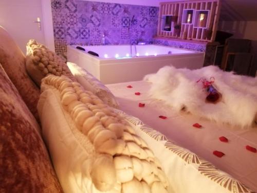 a bedroom with a tub and a bed with flowers on it at Escapade Veyloise-Nuit romantique-Spa-Champagne in Pont-de-Veyle