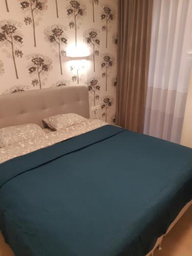 a bedroom with a bed with a blue blanket and a lamp at Apartment in Druskininkai City Centre in Druskininkai