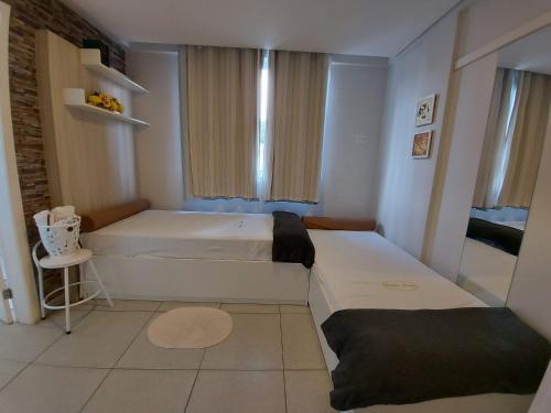 a small bedroom with two beds and a window at Villa Tata Suites in Curitiba