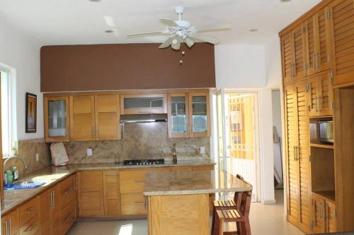 a kitchen with wooden cabinets and a ceiling fan at Casa del faro 80, con vista al mar in Manzanillo