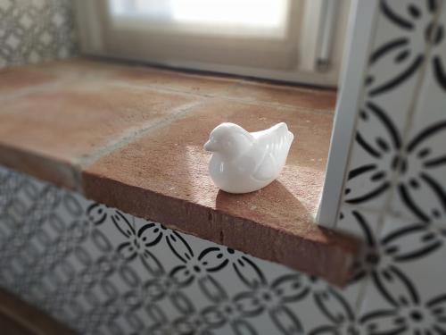 a white bird figurine sitting on a ledge in front of a mirror at Casa Mantel Holiday Home Panoramic view in Langhe in Novello