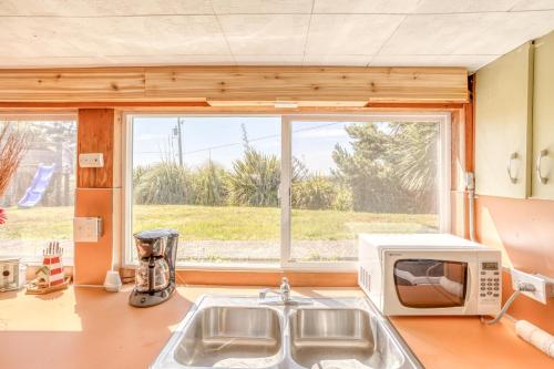 a kitchen with a microwave and a sink and a window at Sea Haven in Lincoln City