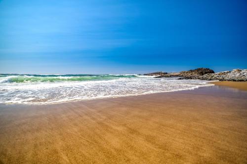 a sandy beach with waves and rocks in the ocean at Sea Haven in Lincoln City