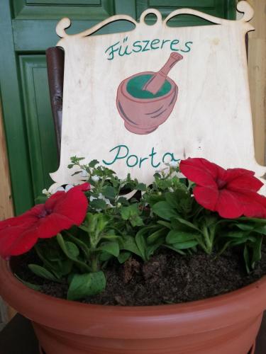 a flower pot with red flowers and a sign at Fűszeres Porta in Mihályfa