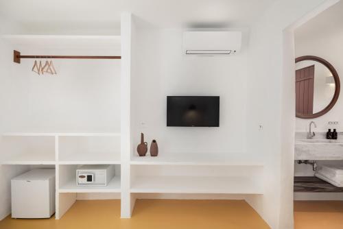 a room with white walls and a tv on a wall at Miradouro de São Sebastião in São Sebastião