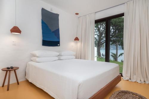 a white bedroom with a bed and a window at Miradouro de São Sebastião in São Sebastião