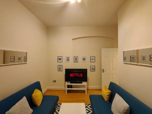 a living room with a blue couch and a tv at Newhall Street Apartment in Birmingham