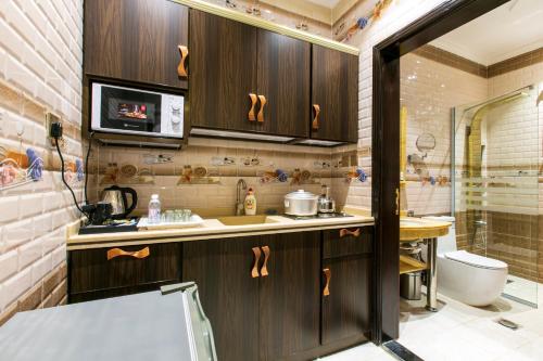 a kitchen with wooden cabinets and a sink and a shower at Lambert ApartHotel in Jeddah